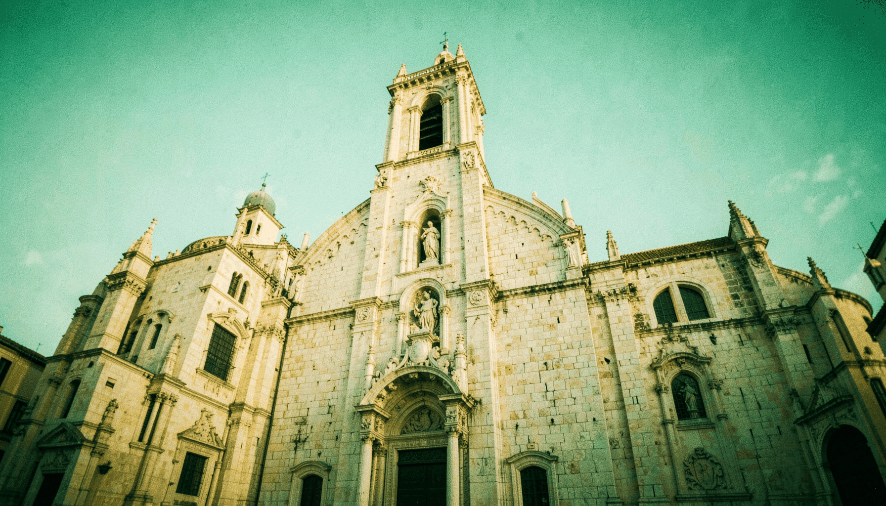 Fachada de piedra clara de una catedral aragonesa con torre y detalles renacentistas bajo luz cálida